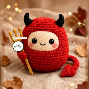 May include: A round red crochet plush toy with black horns, a pointed tail, and a cream-colored face with black eyes and a small smile. The toy holds a yellow crochet trident. Text on the image reads: INSTANT DOWNLOAD, PDF PATTERN, EASY.