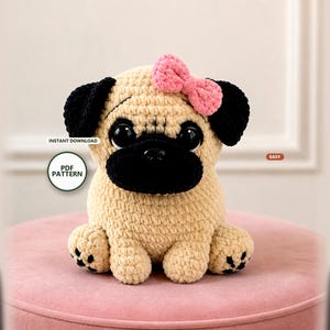 Peut inclure: Un jouet en peluche carlin au crochet en fil beige, avec des oreilles et un museau noirs. Il possède de grands yeux sombres et un petit nœud en fil rose sur la tête. Le jouet a quatre pattes avec des détails noirs cousus. Le texte indique : INSTANT DOWNLOAD PDF PATTERN EASY.