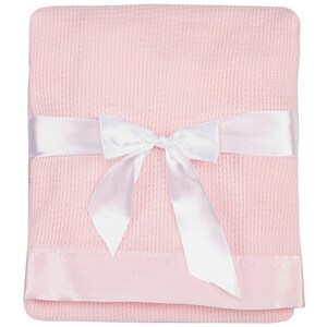 May include: A pink waffle weave baby blanket with a white satin ribbon tied in a bow. The blanket has a satin trim around the edges.