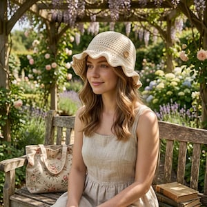 May include: A cream-colored crochet bucket hat with a wide, wavy brim and a single wooden button detail on the side, paired with a sleeveless beige dress and a floral print tote bag featuring a pattern of pink roses and green leaves.