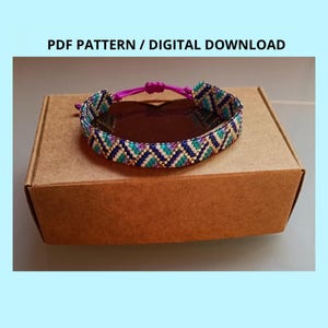 May include: A woven beaded bracelet featuring a geometric chevron pattern in shades of dark blue, teal, white, and gold. The bracelet includes a bright magenta adjustable cord closure. The text PDF PATTERN / DIGITAL DOWNLOAD is visible.