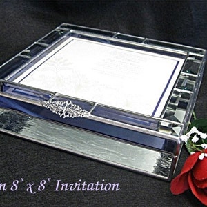 May include: A clear glass box with a blue stained glass border and a silver metal accent. The box is designed to hold an 8 x 8 inch invitation. "For an 8 x 8 Invitation" is written below the box.