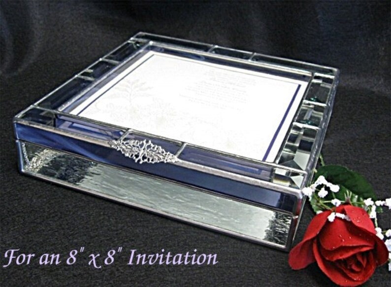 May include: A clear glass box with a blue stained glass border and a silver metal accent. The box is designed to hold an 8 x 8 inch invitation. "For an 8 x 8 Invitation" is written below the box.