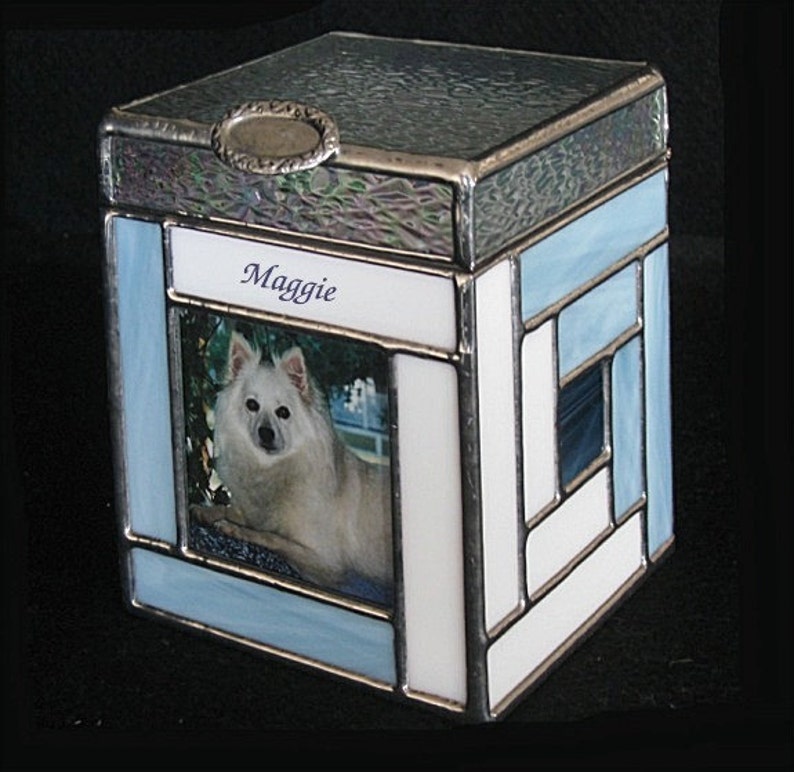 May include: A blue and white stained glass box with a photo of a white dog and the name "Maggie" on the front.