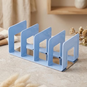 Pode incluir: Um organizador de plástico azul-claro com quatro divisórias verticais fixadas a uma base retangular. A estrutura possui um design aberto com bordas lisas e arredondadas, oferecendo múltiplos compartimentos para armazenamento vertical de itens.