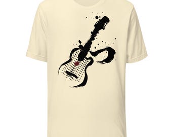 May include: A cream-colored short-sleeve t-shirt featuring a black ink-wash style graphic of an electric guitar. The guitar design incorporates a grid of black dots on the body, a single red dot in the center, and abstract brushstroke accents.