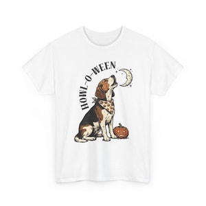 Könnte beinhalten: Ein weißes T-Shirt mit kurzen Ärmeln und einer Grafik eines Beagles, der ein Bandana mit Kürbismuster trägt. Der Hund heult einen Halbmond an, neben ihm steht ein geschnitzter Kürbis. Der Text HOWL-O-WEEN ist bogenförmig darüber gedruckt.