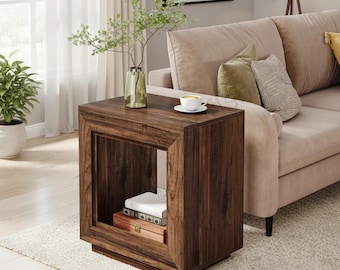 Puede incluir: Una mesa auxiliar de madera de color marrón oscuro con un diseño de marco cuadrado y un compartimento de almacenamiento central abierto. La mesa presenta un acabado de veta de madera lisa, una superficie superior plana y una base empotrada.