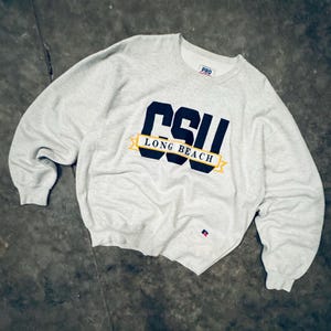 May include: A grey sweatshirt with a black and yellow embroidered logo that says "CSU LONG BEACH" and a small red and blue logo on the bottom right.