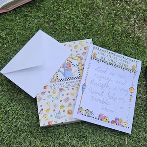 May include: A white envelope, a patterned greeting card featuring a blue watering can, and a white card with the text God shall supply all your needs, God is our refuge and strength, a very present help in trouble, Psalm 46:1, and birdhouse art.