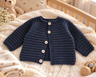 May include: A dark navy blue long-sleeved cardigan featuring a ribbed knit texture and five light-coloured circular buttons down the front centre. The garment has a round neckline and raglan sleeves, showcasing a consistent stitch pattern throughout.