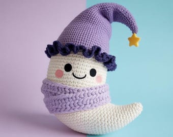 May include: A crescent moon-shaped crochet plush toy in cream white, wearing a purple pointed hat with a dark purple ruffled trim and a small yellow star at the tip. The plush features a thick, light purple knitted scarf and embroidered face.