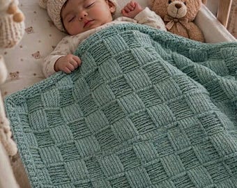 May include: A sage green knitted baby blanket featuring a textured basketweave pattern. The blanket is draped over a sleeping infant wearing a cream-coloured knit hat and a long-sleeved top, positioned next to a brown plush teddy bear with a bow.