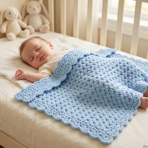 May include: A light blue crocheted baby blanket with a scalloped edge, featuring a textured stitch pattern. The blanket is draped over a sleeping infant who is wearing a plain white short-sleeved onesie, resting on a white sheet in a crib.