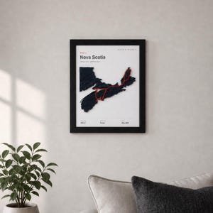 May include: A framed wall art print featuring a dark blue textured map of Nova Scotia on a white background. A thin red line traces a route across the landmass. Text includes Nova Scotia, Hiking Trip, Spring 2024, 850 mi, 8 Days, May 2024.