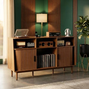 May include: A wooden media console featuring two tambour-style sliding doors, open shelving, and tapered legs. The unit holds a record player, various audio equipment, and a collection of vinyl records stored in the central open compartment.