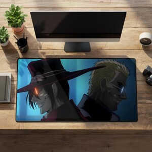 May include: A rectangular desk mat featuring a graphic illustration of two anime characters back-to-back. One character wears a wide-brimmed red hat with a glowing eye, while the other has blonde hair and wears glasses. The background is a dark blue.