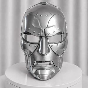 May include: A metallic silver full-face mask featuring a segmented design with visible rivets along the brow, cheekbones, and jawline. The mask has rectangular eye openings and a distinct, articulated mouth section with a prominent chin piece.