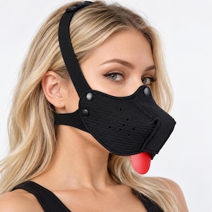 May include: A black neoprene animal-style muzzle mask featuring a textured surface, black snap button accents, and a protruding red tongue. The mask is secured with an adjustable black elastic head strap that wraps around the crown of the head.