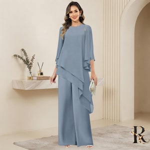 May include: A dusty blue floor-length jumpsuit featuring a sleeveless bodice with a layered, asymmetrical chiffon overlay that drapes over the shoulders and down the front. The garment has a round neckline and wide-leg trousers in a solid color.