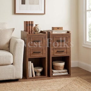 May include: Two matching narrow wooden nightstands, each featuring two drawers with dark metal handles and an open bottom shelf. The units are finished in a medium brown wood tone and are styled with books, a small decorative bowl, and a woven basket.