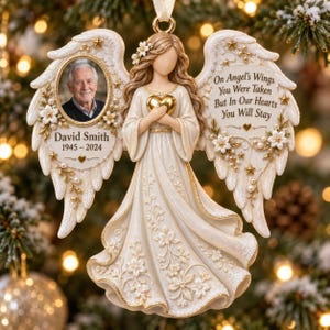 Könnte beinhalten: Ein cremefarbener Engel-Anhänger mit goldenen Akzenten, der ein Foto eines älteren Mannes, den Text David Smith 1945-2024 und die Inschrift On Angel's Wings You Were Taken But In Our Hearts You Will Stay sowie florale Details zeigt.