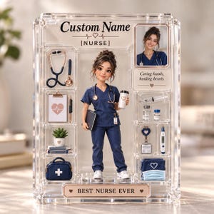 Puede incluir: Una vitrina de acrílico transparente con una figura central de enfermería en uniforme azul marino sosteniendo una taza de café y un cuaderno. La vitrina incluye espacios para un estetoscopio, portapapeles, planta, bolsa médica y el texto "BEST NURSE EVER".