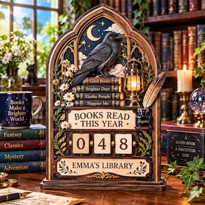 Könnte beinhalten: Ein hölzernes, bogenförmiges Bücher-Tracking-Display mit einem schwarzen Raben, einer Miniatur-Laterne und Büchern mit den Titeln Good Books, Brighter Days, Kinder People und Happier Me. Es zeigt die Zahl 048 und den Text Emma's Library.