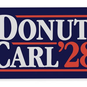 Può includere: Un cartello rettangolare con sfondo blu scuro che presenta il testo DONUT in grandi lettere bianche, seguito da CARL '28 in lettere bianche e rosse, accentuato da due linee orizzontali rosse sopra e sotto il testo.