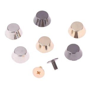 May include: A collection of six conical metal studs in silver, gold, and gunmetal finishes, arranged in a circular pattern. Each stud features a flat circular top and a tapered base. Two separate metal screws with flat heads are positioned below.