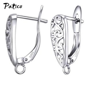 May include: A pair of silver-toned metal earring findings with a filigree cutout pattern and a hinged lever back closure. Each piece is stamped with S925 and features a small circular loop at the bottom for attaching charms or pendants.