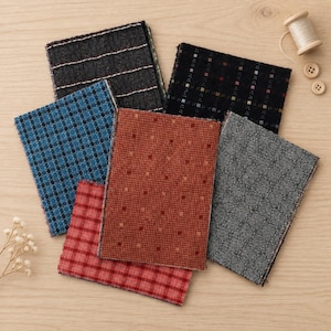 May include: A collection of six rectangular fabric swatches featuring various patterns including plaid, checkered, and dotted designs in black, blue, red, orange, and gray. A wooden spool of thread and two small wooden buttons are also visible.
