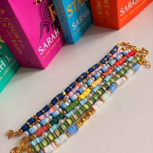 May include: A collection of five handmade bracelets featuring colourful polymer clay heishi beads, interspersed with white faux pearls and small gold-toned metal spacers. Each bracelet is finished with a gold-toned lobster claw clasp and extender chain.