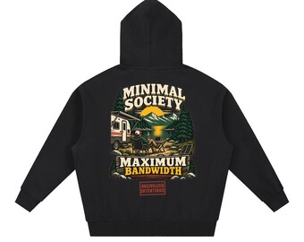 Puede incluir: Una sudadera con capucha negra que presenta un gráfico en la espalda de una persona sentada en una silla de camping con un portátil cerca de una caravana, un lago y montañas. El texto dice MINIMAL SOCIETY, MAXIMUM BANDWIDTH y UNCIVILIZED INTENTIONS.