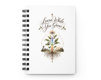 May include: A white spiral-bound notebook featuring a central graphic of a plant with seven colored chakra circles along its stem, roots at the base, and an eye symbol above. The text "Learn While You Grow" is printed in black cursive script.