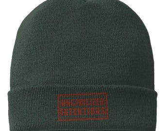 May include: A dark forest green knit beanie with a cuffed brim. Centered on the cuff is a rectangular patch featuring the text UNCIVILIZED INTENTIONS embroidered in a deep red thread, enclosed within a matching red rectangular border outline.