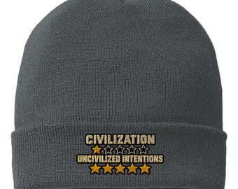 May include: A charcoal grey knit beanie featuring embroidered text that reads CIVILIZATION above a single gold star and four empty star outlines, followed by UNCIVILIZED INTENTIONS above five solid gold stars, all centred on the folded cuff.