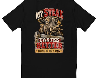 May include: A black short-sleeve t-shirt featuring a graphic of a cow behind a wooden fence. The text reads MY STEAK TASTES BETTER BECAUSE HE HAD A NAME. The cow has an ear tag that says EARL. The design uses red, white, and brown colors.