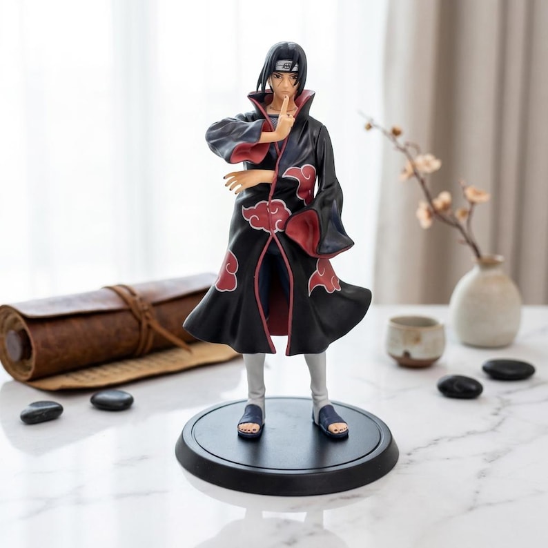 May include: A standing anime character figurine featuring a person with black hair wearing a long black coat with red cloud patterns and a high collar. The figure is posed with one hand near the face, wearing light gray pants and dark blue sandals.