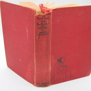 May include: A red hardcover book titled "Hard Times and The Owl in the Attic" by James Thurber. The book cover features a black and white illustration of a woman sitting in a chair with a cat.