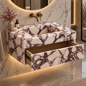 May include: A wall-mounted bathroom vanity featuring a rectangular sink basin and a single pull-out drawer. The exterior is crafted from white marble with prominent dark red veining. The drawer front has a vertical ribbed texture.