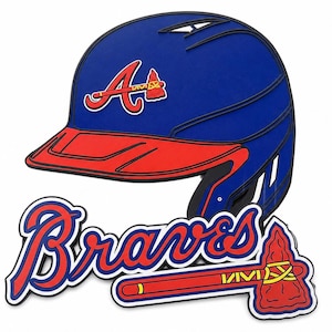 Puede incluir: Un letrero de pared en capas que muestra un casco de bateo de béisbol azul con visera roja y el logotipo de los Atlanta Braves. Debajo del casco, la palabra Braves está escrita en letra roja, acompañada de un icono de tomahawk rojo con detalles amarillos y blancos.