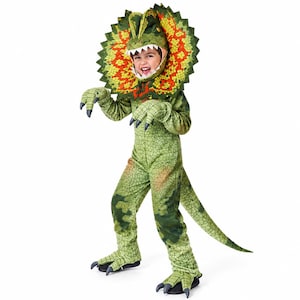 May include: A green dinosaur costume featuring a textured, scaly skin pattern, a long tail, and a large, circular neck frill with vibrant orange and yellow accents. The headpiece includes a hood with sharp white teeth framing the face.