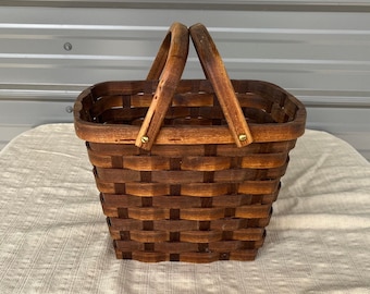 May include: A brown wooden basket with two handles. The basket is woven and has a rectangular shape.