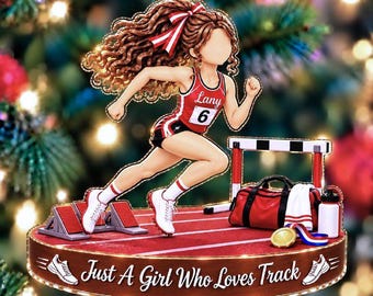May include: A decorative ornament featuring a runner with long brown curly hair and a red and white bow, wearing a red tank top with the name Lany and number 6, on a red track with a hurdle, a red duffel bag, and the text Just A Girl Who Loves Track.