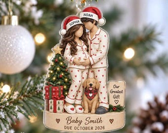 May include: A clear acrylic Christmas ornament featuring a pregnant person and a partner in matching white pajamas with red hearts, wearing Santa hats labeled Sophia and Noah. A golden retriever, a Christmas tree, and a sign reading Our Greatest Gift are included, with the text Baby Smith DUE OCTOBER 2026 on the base.