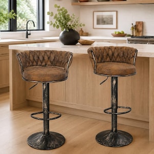 May include: Two adjustable bar stools featuring brown tufted seats with curved backrests and black metal pedestals with a distressed finish. Each stool includes a circular base, a footrest, and a lever mechanism for height adjustment.