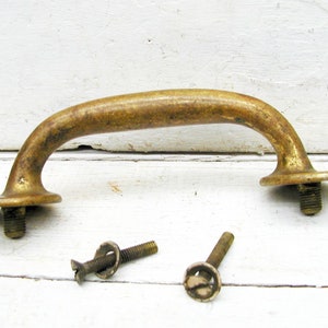 May include: A brass door handle with a curved shape and two round bases. The handle comes with two screws.