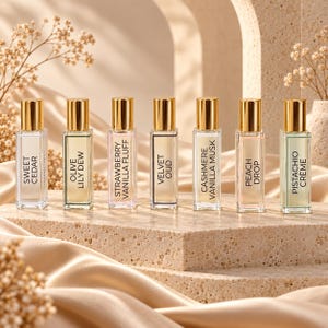 May include: Seven rectangular glass perfume roller bottles with gold caps, each featuring a label with the names Sweet Cedar, Olive Lily Dew, Strawberry Vanilla Fluff, Velvet Oud, Cashmere Vanilla Musk, Peach Drop, and Pistachio Crème.