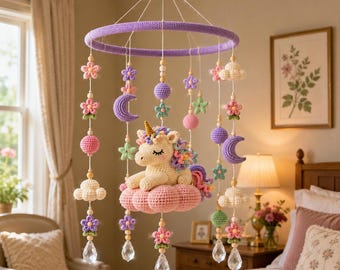 May include: A hanging mobile featuring a central crocheted unicorn resting on a pink cloud. The mobile includes purple, pink, and green crocheted stars, moons, flowers, and clouds, accented with wooden beads and clear crystal-like pendants.
